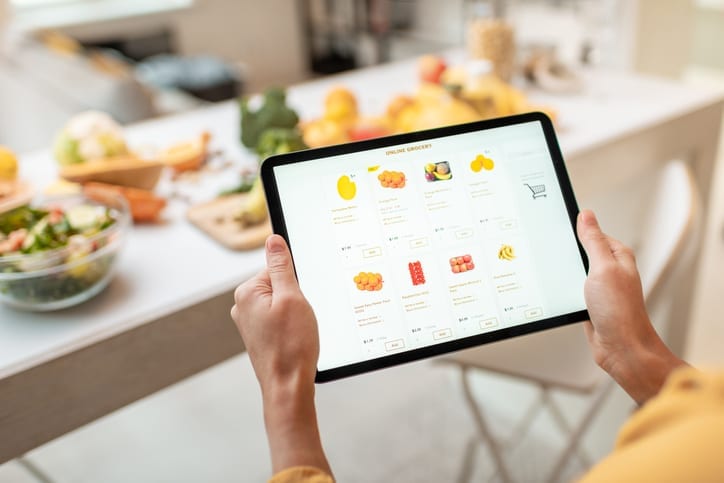 Femme faisant ses courses en ligne à l'aide d'une tablette numérique dans la cuisine, vue rapprochée sur un écran de tablette. Concept d'achat en ligne à l'aide d'appareils mobiles