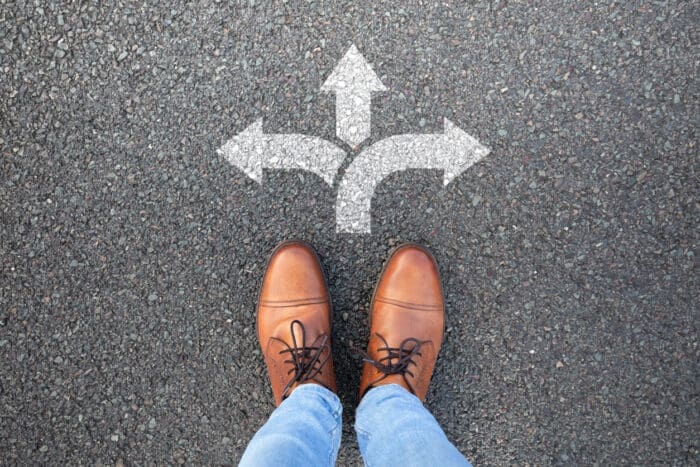 Feet and three-way arrow signs on pavement