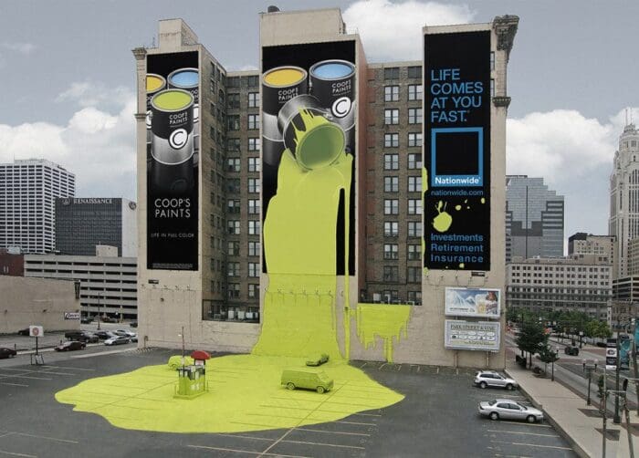 A building mural depicts two large paint cans from Coop's Paints pouring bright yellow paint down the side of the structure, flowing onto a car and the ground below. Utilizing guerrilla marketing, a Nationwide Insurance ad to the right reads, "Life comes at you fast.