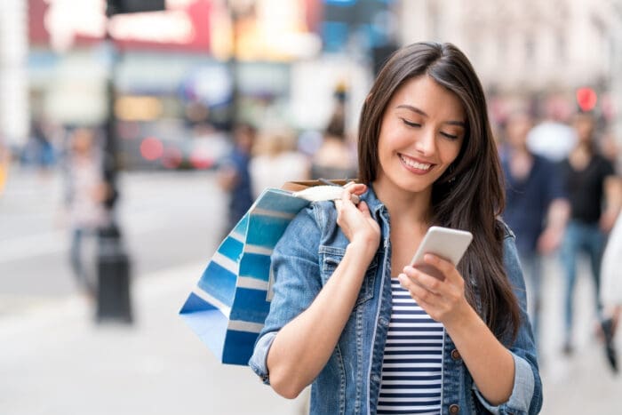 Woman checking phone with shopping bags in city