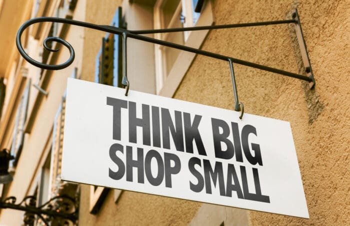 Sign reads &#039;Think Big Shop Small&#039; hanging on metal bracket