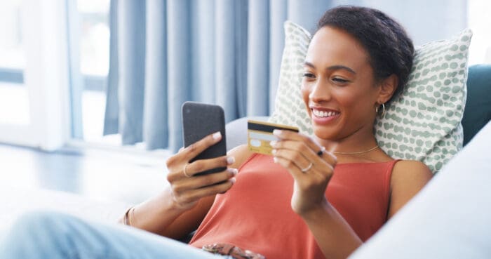 Woman shopping online with smartphone and credit card as an example of customer convenience.