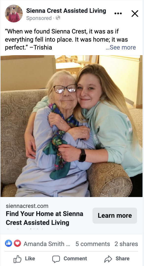 An elderly woman and a young woman share an affectionate embrace while sitting on a couch. Both are smiling warmly. The image is part of a Facebook post for Sienna Crest Assisted Living, featuring a testimonial from Trishia, highlighting the warmth and care provided in senior living.