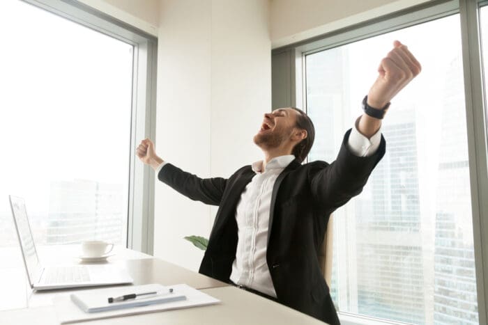 Person celebrating success at office desk.