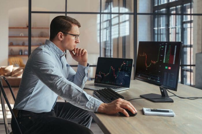 Man analyzing price elasticity data on multiple computer screens