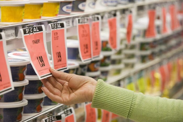 Person checking price tags on grocery store shelf. What is price elasticity?