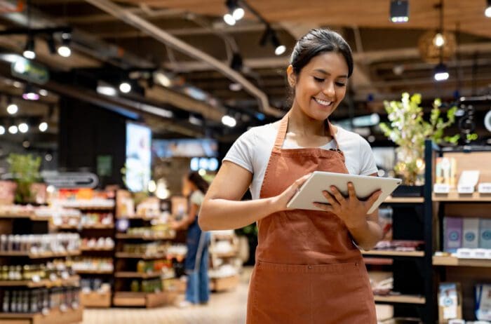 Smiling woman with tablet in modern grocery store