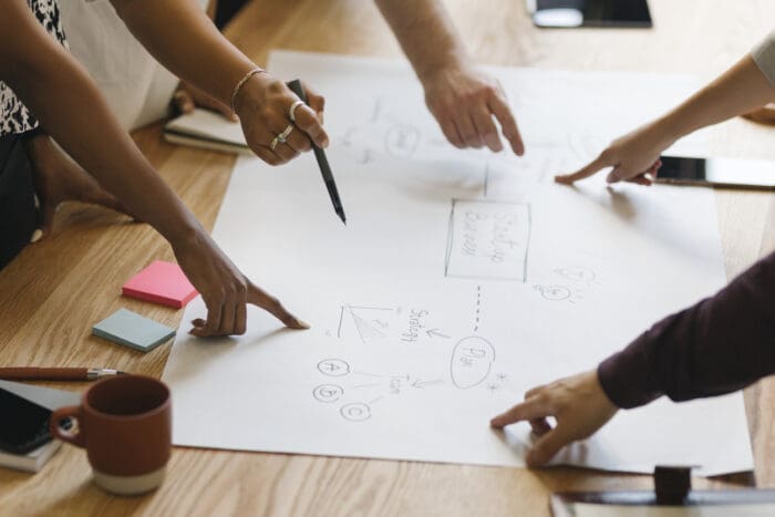 Hands collaborating on business strategy diagram.