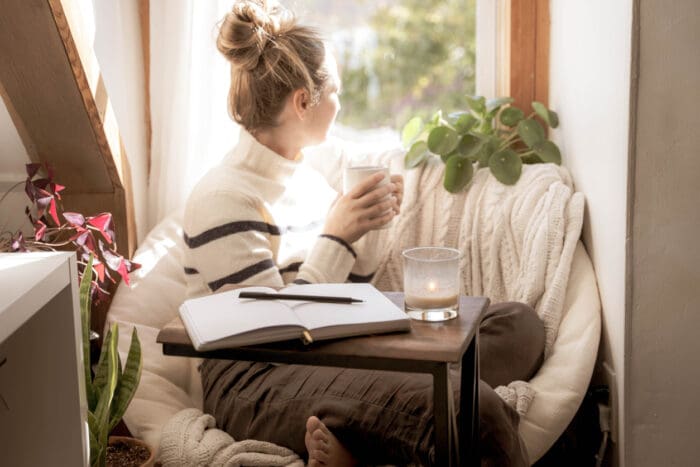 Woman enjoying coffee in cozy, sunlit window seat