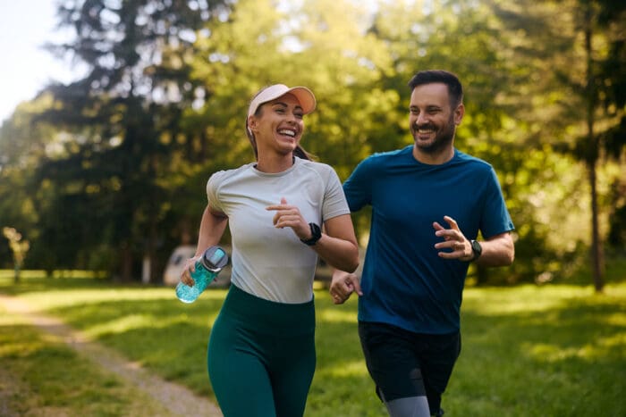 Couple jogging joyfully in sunny park