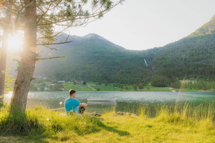 Man sitting by serene lake with mountain backdrop