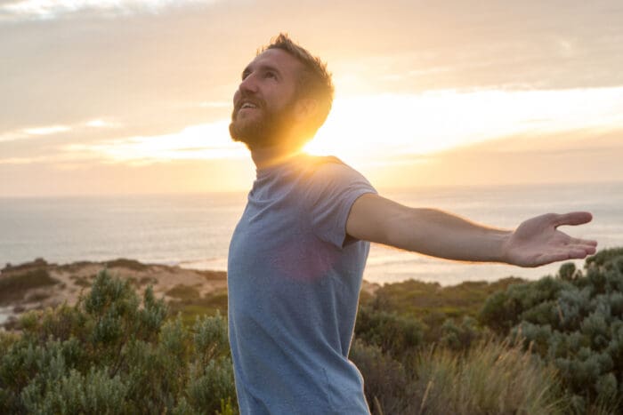 Man embracing sunrise by the sea - keep calm