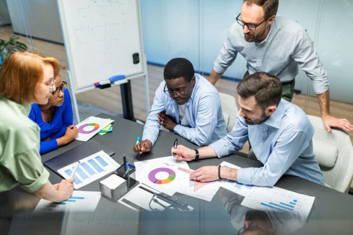 Image of business professionals analyzing graphs and charts on a conference table, symbolizing comparison and evaluation of data for competitive benchmarking.