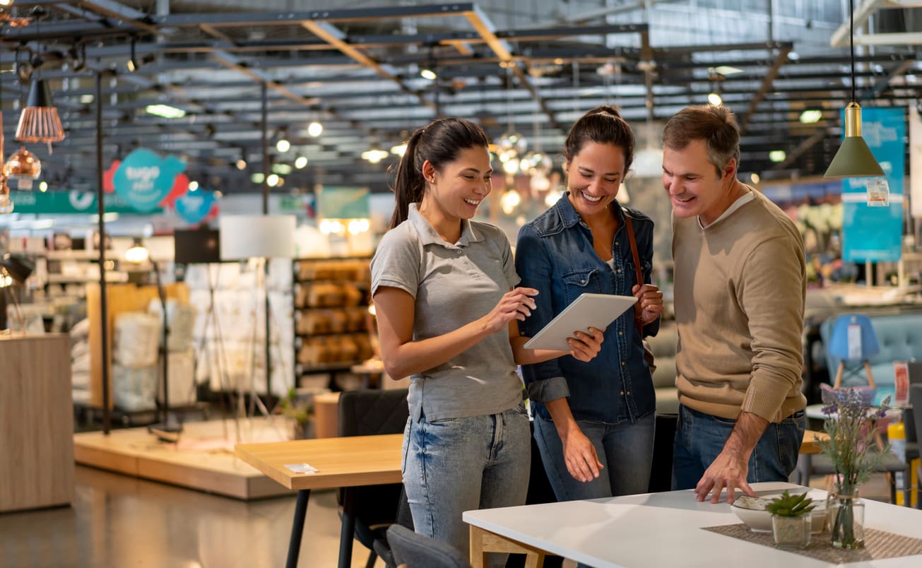 Three adults using tablet in furniture store