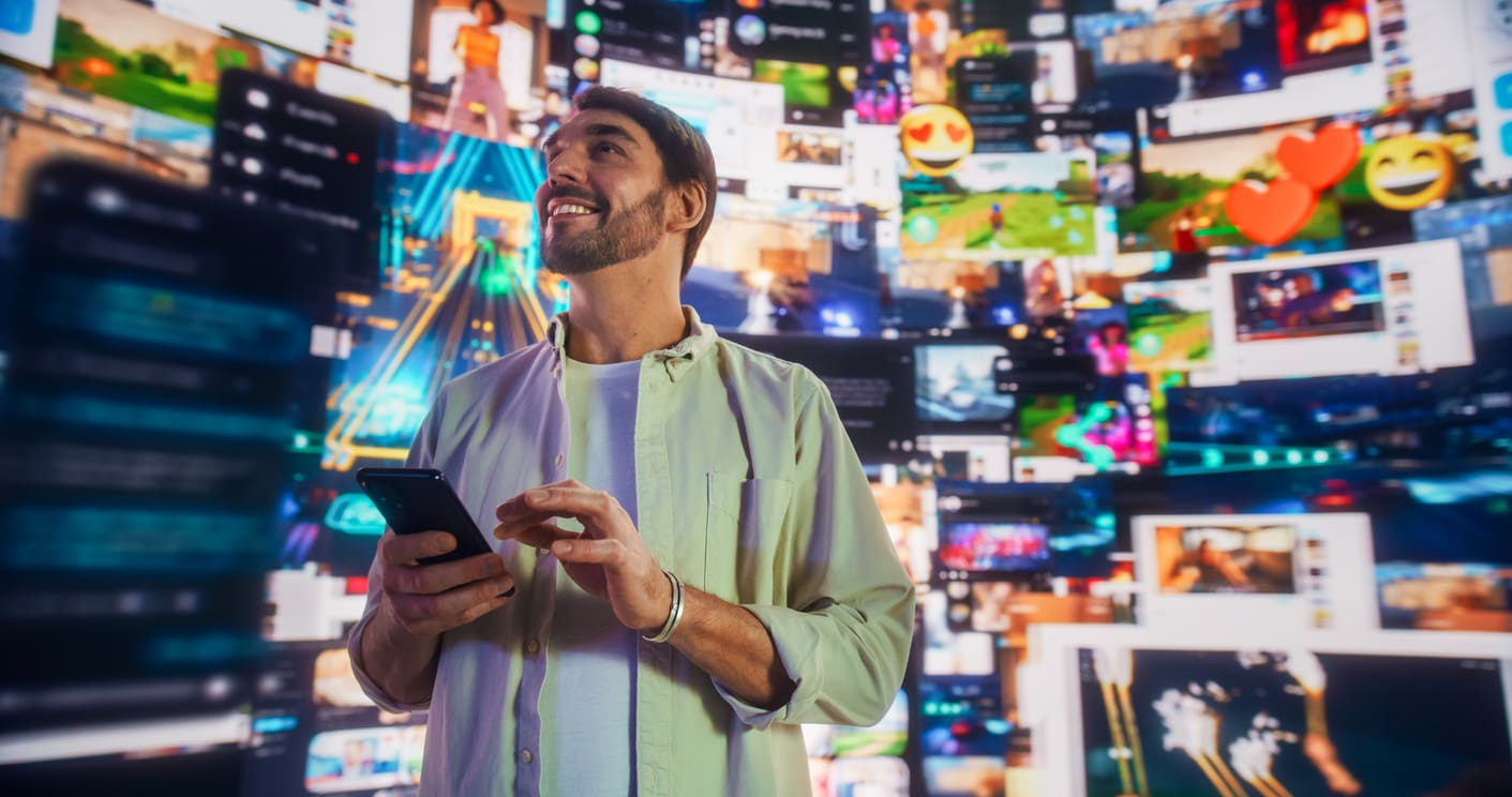 A man stands surrounded by a vast array of floating digital screens displaying social media content, videos, and emojis. He holds a smartphone, looking upwards and smiling, as if interacting with a vibrant virtual environment designed to boost brand affinity.