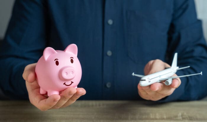 Balancing finance and travel with piggy bank, airplane.