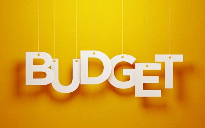 White 3D letters spelling 'BUDGET' on yellow background.