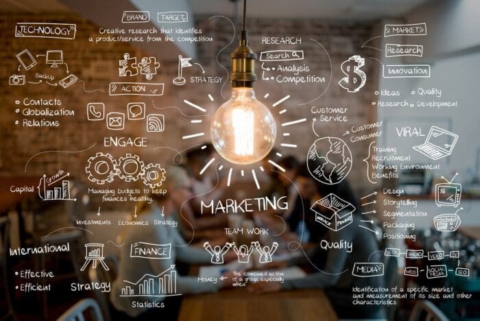 Illuminated light bulb with marketing strategy doodles on glass