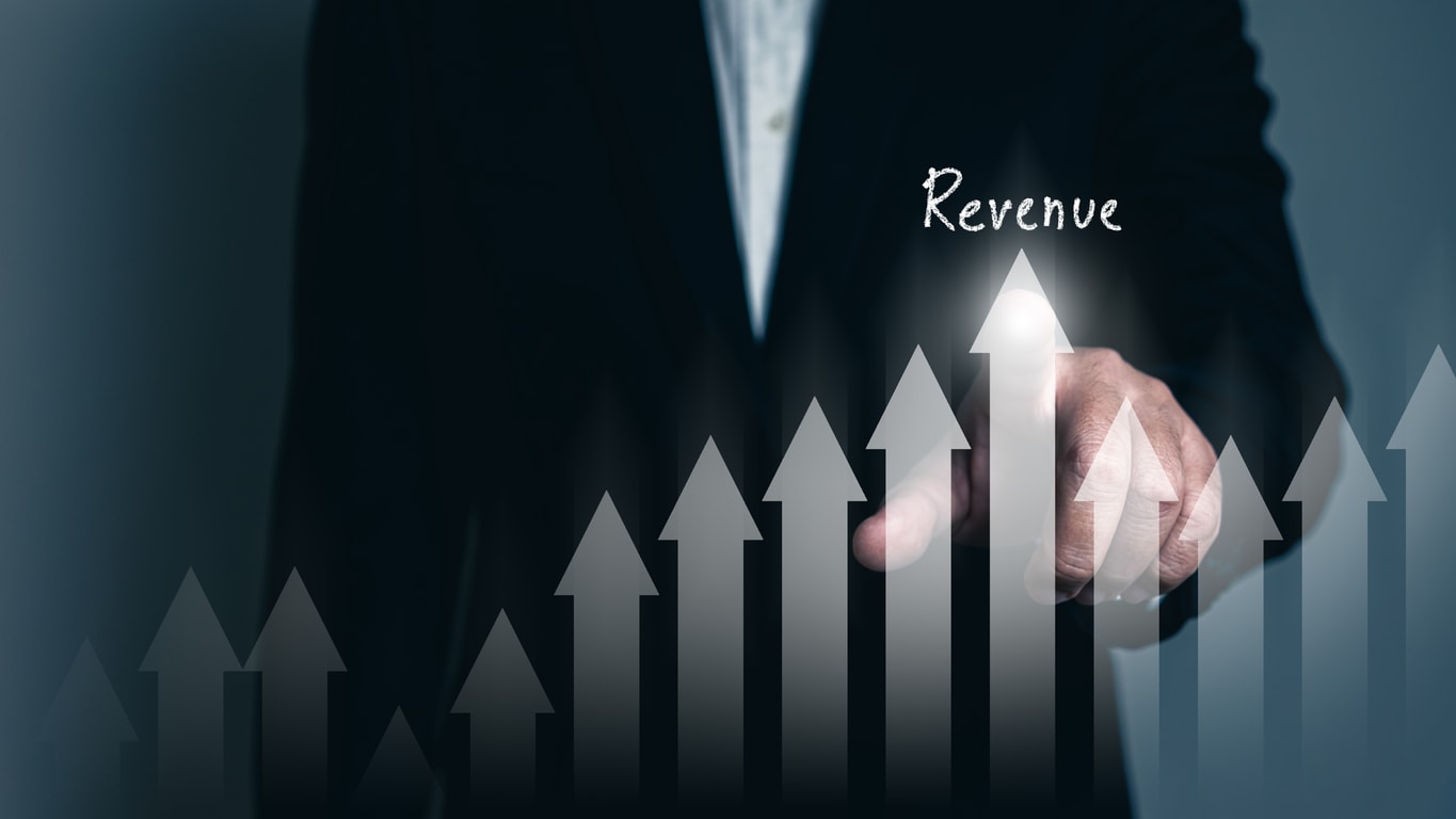 Businessman pointing at rising arrows labeled Revenue