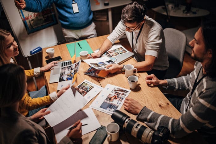 Creative team discussing photos at cluttered table