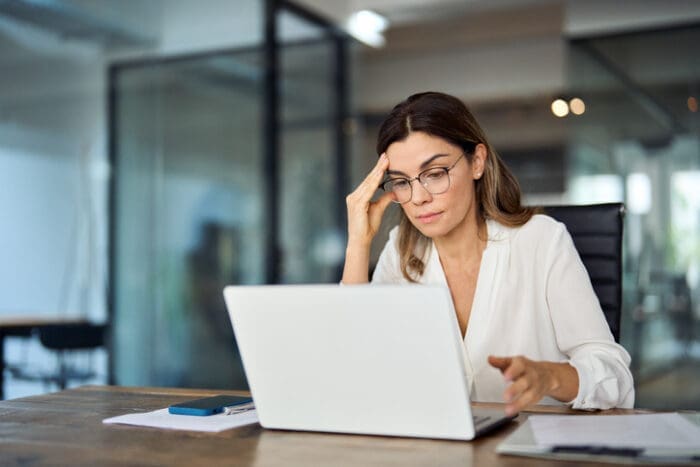 Woman in white blouse using laptop at modern office