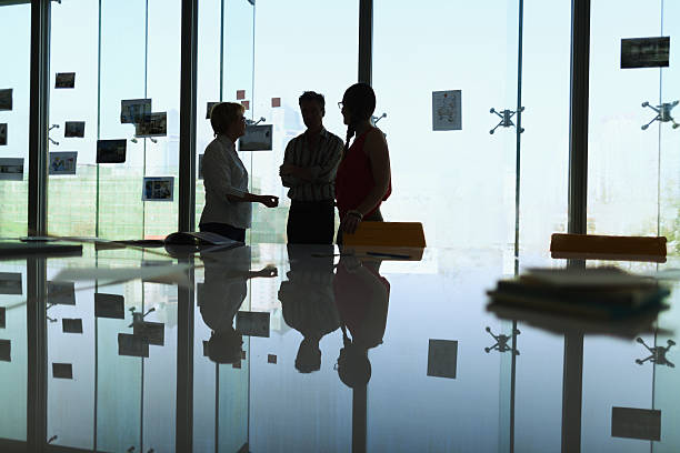 Silhouetted businesspeople discussing in modern office