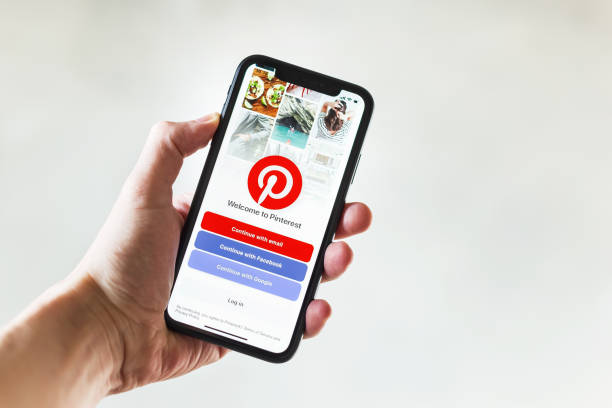 Hand holding smartphone displaying Pinterest login screen
