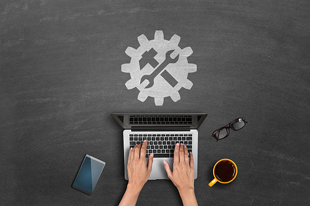 Hands typing on laptop with tools icon.